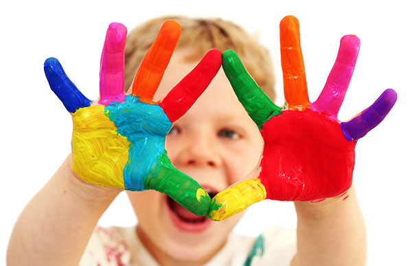 Young boy with brightly coloured painted hands